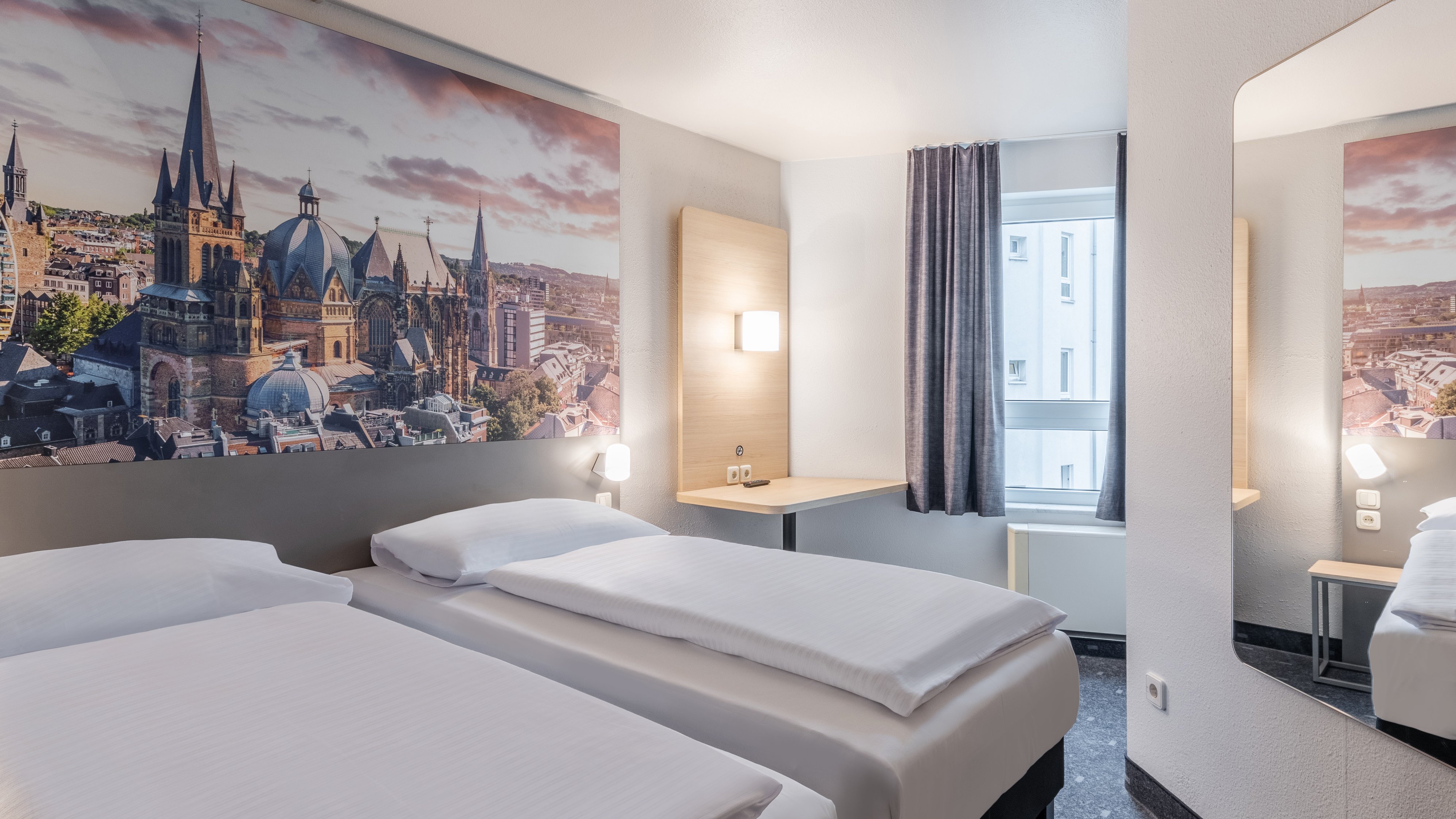 Ein Hotelzimmer mit zwei Betten, einem großen Bild an der Wand und einem kleinen Tisch.